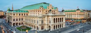 Historic Vienna State Opera House illuminated at dusk in central Vienna, Austria, with grand neo-Renaissance architecture and city streets surrounding the landmark.