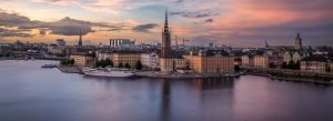 Panoramic sunset view of Stockholm city skyline with historic waterfront buildings and churches in Sweden.