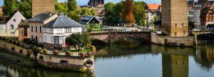 Historic canal, bridge, and traditional architecture in Strasbourg, France during a sunny day
