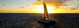 Catamaran sailing at sunset in St. Lucia with golden Caribbean sky