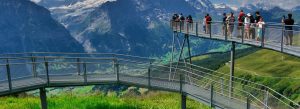 Visitors walking on the First Cliff Walk suspended bridge in Grindelwald with panoramic Swiss Alps mountain views