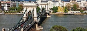 Széchenyi Chain Bridge crossing the Danube River in Budapest, Hungary with historic city architecture in the background.