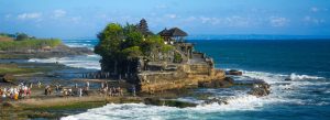 Tanah Lot Temple perched on a rocky coastline in Bali, Indonesia, with ocean waves crashing around the temple.