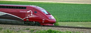 Red Thalys high-speed train traveling through the countryside from Amsterdam to Paris