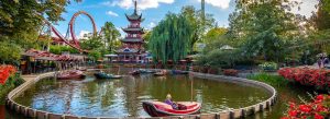 Visitors enjoying boat rides and roller coasters at Tivoli Gardens amusement park in Copenhagen, Denmark.