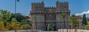 Torres de Serranos medieval gate in Valencia, Spain, viewed from the bridge with palm trees and blue sky