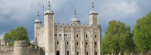 Historic Tower of London fortress with white stone walls and medieval towers under a cloudy sky in London, England.