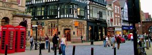 Historic Tudor-style buildings and traditional red telephone boxes in the town center of Chester, England.