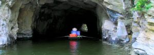 Small rowing boat entering a limestone cave in Trang An Landscape Complex, Ninh Binh, Vietnam