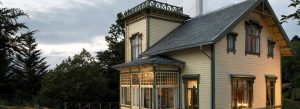 Historic Troldhaugen villa in Bergen, Norway, surrounded by trees at dusk with illuminated windows and traditional Norwegian architecture.