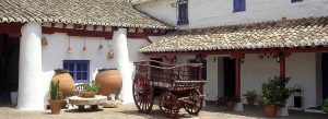 Traditional Venta del Quijote courtyard in Puerto Lápice, Spain with whitewashed walls, clay roof tiles, and a rustic wooden cart.