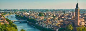 Panoramic aerial view of Verona, Italy, with the Adige River, historic bridges, and medieval architecture at sunset.