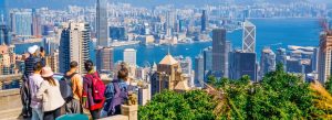 Tourists enjoying panoramic skyline views of Hong Kong Harbour from Victoria Peak observation deck.