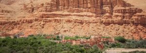 Traditional Berber village in Morocco’s Vallée des Roses surrounded by lush greenery and dramatic red rock cliffs.