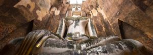 Massive seated Buddha statue inside Wat Si Chum Temple ruins in Sukhothai Historical Park, Thailand.