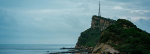 Rocky coastal cliffs and lush green hills at Yehliu Geopark in Taiwan under a dramatic cloudy sky.