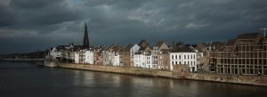 Panoramic riverside view of Maastricht city with historic buildings and dramatic cloudy sky in the Netherlands