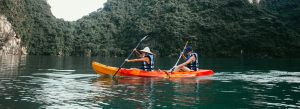 Tourists kayaking across the calm emerald waters of Hạ Long Bay surrounded by towering limestone cliffs in Vietnam
