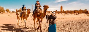 Travelers riding camels through the desert near M’Hamid in Morocco